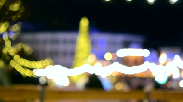 人们在露天溜冰场上滑冰 在冬天的夜晚 在城市里有一棵巨大的圣诞树 在新年和圣诞节的灯火通明的装饰和街道装饰 模糊的背景 — 图库视频影像