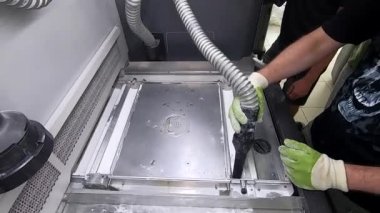 Bir erkek işçi, elektrikli süpürgeyle endüstriyel 3D yazıcının yüzeyini beyaz tozdan temizliyor. Çoklu Jet Füzyon MJF 3D baskı. Çalışma süreci