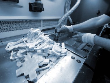 Adam, endüstriyel 3D yazıcıda beyaz plastik tozdan basılmış detayları temizliyor. Otomatik katkı teknolojileri. İnsan, 3 boyutlu yazıcıdan çıkan elektrikli süpürge tozunu temizliyor. Üst görünüm