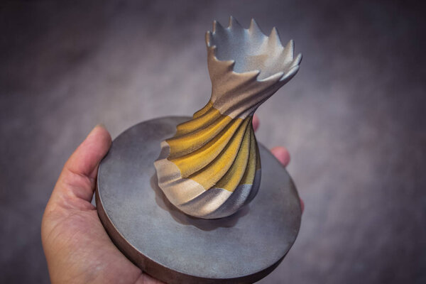 Человек держит объект, напечатанный на металлическом 3D принтере. Объект, отпечатанный в машине лазерного спекания. Современная 3D печать принтера из металлического порошка. Технология прогрессивной аддитивной печати DMLS, SLM, SLS 3d