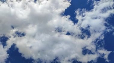 Zaman ayarlı. Mavi gökyüzünde hızla ilerleyen beyaz ve gri fırtına bulutları. Doğal soyut arka plan. Atmosfer, hava. Güneşli bir gün. Konsept çevre, çevre koruma, ekoloji, eko