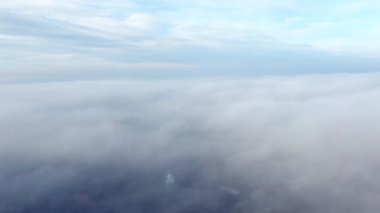 Sis sisi ve binaların çatıları üzerinde ve gökyüzündeki beyaz bulutların altında uçan hava aracı görüntüsü. Soyut doğal arkaplan. Hava bulutlu. Atmosfer. Üst görünüm sis bulutlu hareket