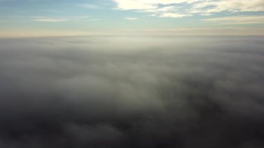 Sis sisi ve binaların çatıları üzerinde ve gökyüzündeki beyaz bulutların altında uçan hava aracı görüntüsü. Soyut doğal arkaplan. Hava bulutlu. Atmosfer. Üst görünüm sis bulutlu hareket