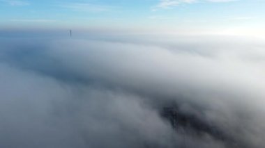 Sis sisi ve binaların çatıları üzerinde ve gökyüzündeki beyaz bulutların altında uçan hava aracı görüntüsü. Soyut doğal arkaplan. Hava bulutlu. Atmosfer. Üst görünüm sis bulutlu hareket