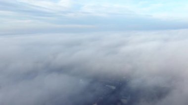 Sis sisi ve binaların çatıları üzerinde ve gökyüzündeki beyaz bulutların altında uçan hava aracı görüntüsü. Soyut doğal arkaplan. Hava bulutlu. Atmosfer. Üst görünüm sis bulutlu hareket