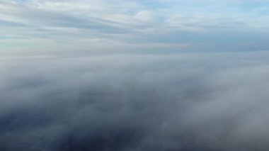 Sis sisi ve binaların çatıları üzerinde ve gökyüzündeki beyaz bulutların altında uçan hava aracı görüntüsü. Soyut doğal arkaplan. Hava bulutlu. Atmosfer. Üst görünüm sis bulutlu hareket