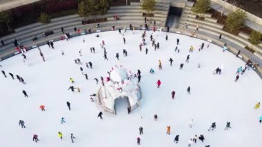 Many people are skating on a white outdoor ice rink in the city on winter day. People skating on the surface of a white ice rink. Aerial drone view. Top view. Lifestyle, sport, rest