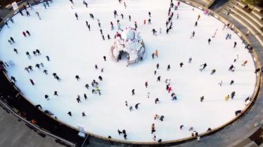 Many people are skating on a white outdoor ice rink in the city on winter day. People skating on the surface of a white ice rink. Aerial drone view. Top view. Lifestyle, sport, rest