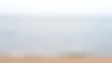Arka plan bulanık. Deniz, deniz dalgaları, kumlu plaj ve bulutlu havada gökyüzü. Yaban hayatı deniz manzarası, doğa, deniz kıyısı, yaz günü deniz kıyısı. Yazın doğal arka plan. Gri bej kahverengi renkler