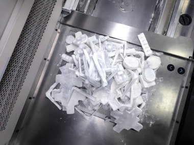 Laboratuvardaki beyaz plastik tozdan endüstriyel 3D yazıcıya basılmış nesneler ve modeller. Çalışma yüzeyi oluşturuluyor. Çoklu Jet Füzyon MJF 3D baskı. Yeni teknolojiler 3D yazıcı