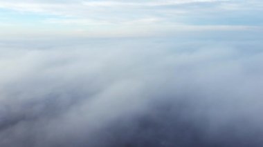 Sis sisi ve binaların çatıları üzerinde ve gökyüzündeki beyaz bulutların altında uçan hava aracı görüntüsü. Soyut doğal arkaplan. Hava bulutlu. Atmosfer. Üst görünüm sis bulutlu hareket