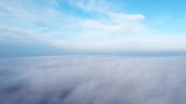 Sis sisi ve binaların çatıları üzerinde ve gökyüzündeki beyaz bulutların altında uçan hava aracı görüntüsü. Soyut doğal arkaplan. Hava bulutlu. Atmosfer. Üst görünüm sis bulutlu hareket