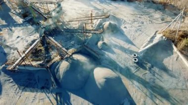 Crushing plant in granite quarry top view. Aerial flight over crusher in granite quarry. Stone crushing. Industrial production of gravel. Gravel conveyor view above. Cone type rock crusher,