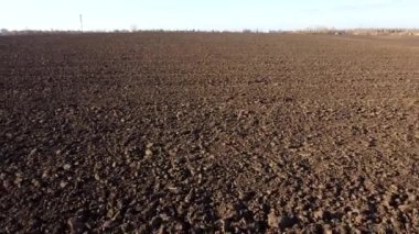 Flying over the plowed fields of black soil on sunny autumn day. Fields black soil close-up. Farming countryside rural. Digged agrarian agricultural earth fields. Plowed lands. Dug up ground farmlands