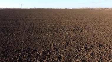 Flying over the plowed fields of black soil on sunny autumn day. Fields black soil close-up. Farming countryside rural. Digged agrarian agricultural earth fields. Plowed lands. Dug up ground farmlands