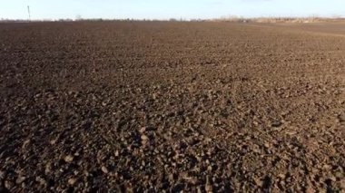 Flying over the plowed fields of black soil on sunny autumn day. Fields black soil close-up. Farming countryside rural. Digged agrarian agricultural earth fields. Plowed lands. Dug up ground farmlands