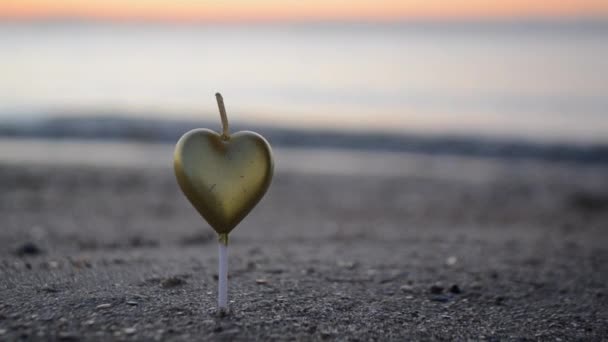 黎明时分 一个男人在沙滩上点燃一支心形的蜡烛 在近照时 在海浪的背景下燃烧心形的蜡烛 浪漫的心情 情人节 — 图库视频影像
