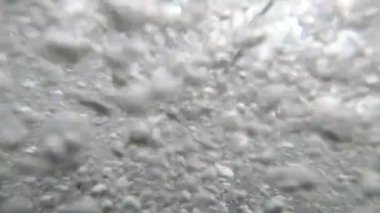 İçeriden deniz dalgası. Bulutlu bir günde, kayalık bir sahilde deniz dalgasının görüntüsü. Hava kabarcıkları yakın plan. Gökyüzündeki bulutlar. Alt manzara. Gri renk. Doğal arkaplan.