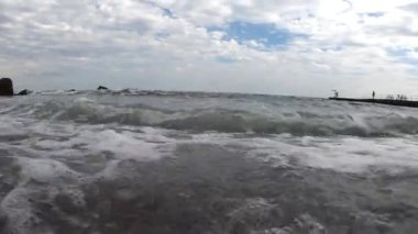 İçeriden deniz dalgası. Bulutlu bir günde, kayalık bir sahilde deniz dalgasının görüntüsü. Hava kabarcıkları yakın plan. Gökyüzündeki bulutlar. Alt manzara. Gri renk. Doğal arkaplan.