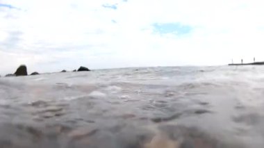 İçeriden deniz dalgası. Bulutlu bir günde, kayalık bir sahilde deniz dalgasının görüntüsü. Hava kabarcıkları yakın plan. Gökyüzündeki bulutlar. Alt manzara. Gri renk. Doğal arkaplan.