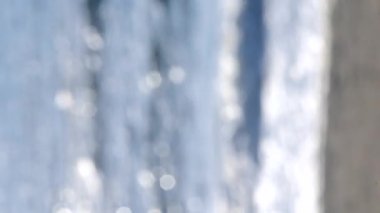 Arka plan bulanık. Yaz güneşli sabahında kumlu sahilde beyaz köpüklü deniz dalgası. Doğal bulanık bokeh dokusu arkaplanı. Güzel doğal arka plan. Çevre, küresel ısınma. Dikey video