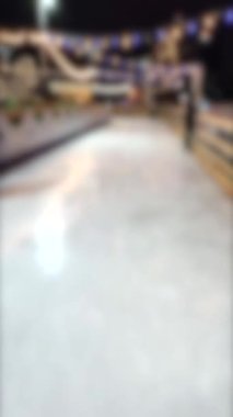 Blurred background. People skating on public open-air ice skating rink in city on winter night. Winter New Year Christmas holidays, decorations illumination garlands flashlights. Vertical video