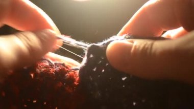 Kadın bir iplik örme yün ürünleri çeker ve siyah arka plan üzerine örme çözülüyor ışık lambaları, yakın çekim. Konu mavi ve kırmızı renk. Parmak ve çivi yakın çekim