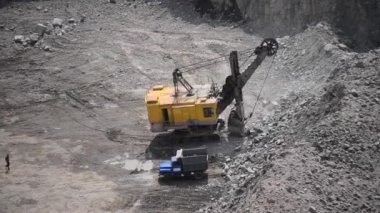 2 video. Büyük endüstriyel kazıcı granit ocaklarında çalışıyor ve kamyonda yükleniyor. Hızlı video HD 1080.Top view Endüstri, madencilik ağır makineleri. Farklı boyutlarda, üst görünümde, sesli.