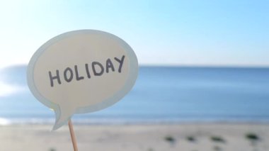 Kağıt konuşma baloncuğuna bağlı kal. Yazın arka planda tatil, gökyüzü, güneşli bir yaz gününde kumlu plaj. Mektuplardan gelen mesajlarla dolu balonlar. Konsept, sembol, tatil gezisi turizmi dinlenmesi.