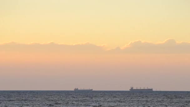タイムラプスだ 海上のスカイラインの穀物運搬船のタンカーのシルエットと日没の夜明けに黄色の青い空に速い移動雲 海の風景です 輸送だ 自然背景 — ストック動画