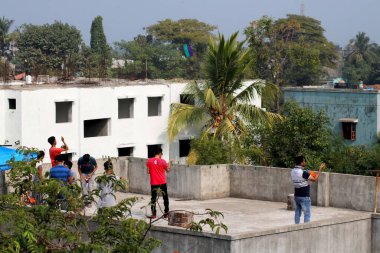 Ülke - Hindistan, Gujarat, Şehir - Valsad Tarihi - 14-01-2021 Bir grup insan terasın tepesinde uçurtma uçurmak için toplandı