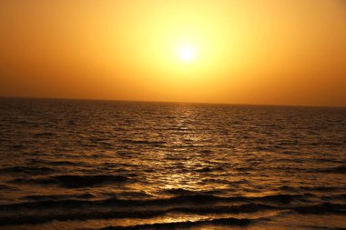 Sahilde gün batımı manzarası ve su yansıması.