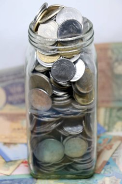 İzole edilmiş arka planda bozuk para dolu cam kavanoz