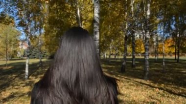 İş kızı, siyah saç arkası, huş ağacı korusu boyunca yürüyor.