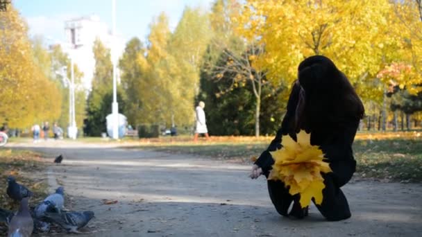 Hübsches brünettes Mädchen füttert Tauben in der Herbststadt — Stockvideo