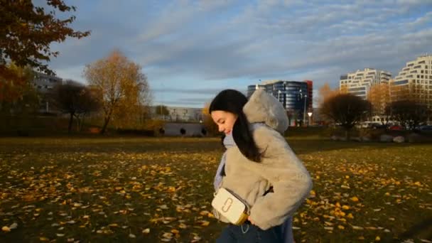 Ein junges Mädchen spaziert abends durch den herbstlichen Stadtpark — Stockvideo