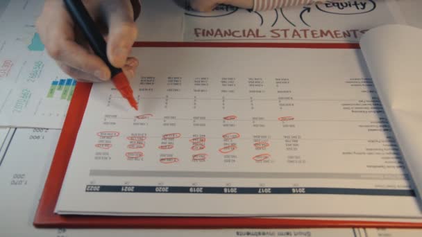 El auditor superior comprueba los estados financieros del año y resalta los datos con un marcador rojo — Vídeo de stock
