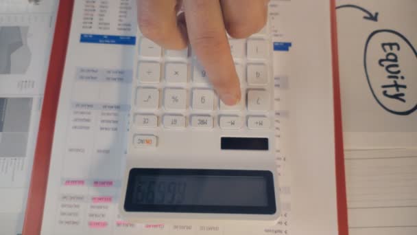 Top view of finger presses keys on a white digital calculator — стоковое видео