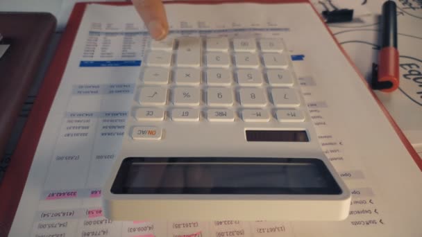 Пользователь, использующий стандартный белый калькулятор для создания финансовых отчетов — стоковое видео
