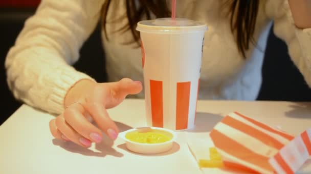Chica comiendo papas fritas en un restaurante de comida rápida — Vídeo de stock