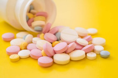 Colored pills for toothache or minstrual pain on yellow background