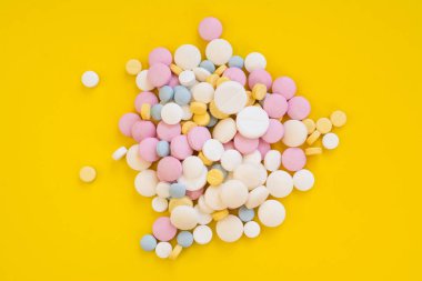 Colored pills for toothache or minstrual pain on yellow background