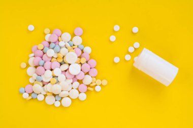 Colored pills for toothache or minstrual pain on yellow background