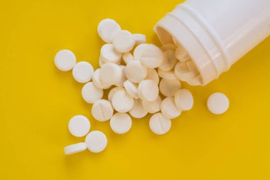 A bunch of pills on a yellow background close up