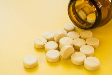 A bunch of pills on a yellow background close up