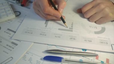İş adamı istatistikleri analiz ediyor ve kalem kullanarak iş raporu grafikleri üzerinde çalışıyor