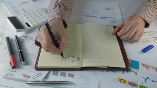 Las manos de los gerentes anotan en un cuaderno en marcador azul los beneficios para 2022 y 2023 — Vídeo de stock