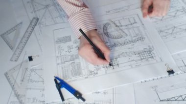 Bir mühendis elinde kalemle endüstriyel bir projenin planlarını kontrol ediyor.