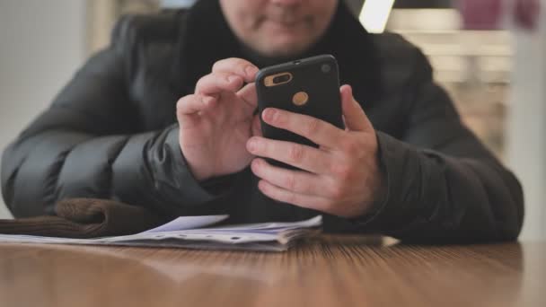 Elinde telefon tutan ve sosyal medya mesajı yazan siyah ceketli bir adamın ön görüntüsü. — Stok video