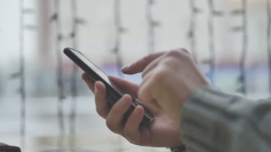 İş adamı elleri pencerenin yanındaki kafede akıllı telefon kullanıyor.